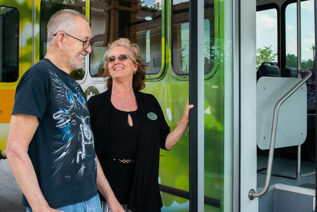 Two people smiling as they stand in the doorway of a bus.