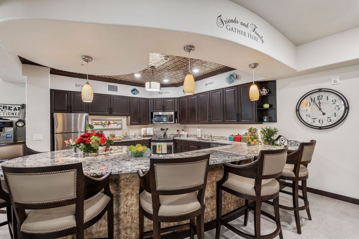 A modern kitchen featuring dark cabinetry, an island with bar stools, and pendant lighting.