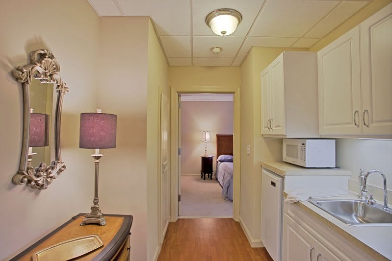 A cozy hallway leading to a bedroom, featuring a small kitchenette and soft lighting.