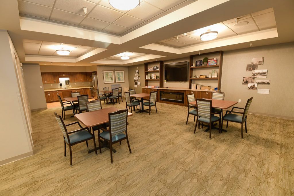 A spacious dining area with neatly arranged tables and chairs, surrounded by shelves and warm lighting.