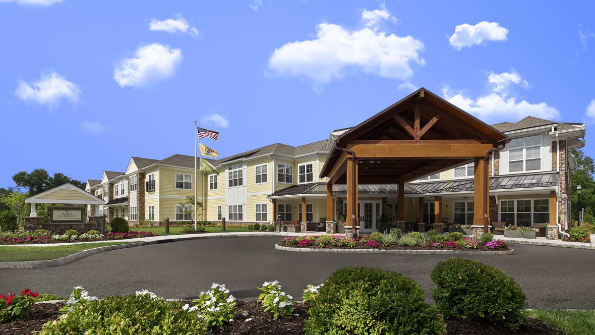 A modern building with a landscaped entrance and American flag against a clear blue sky.