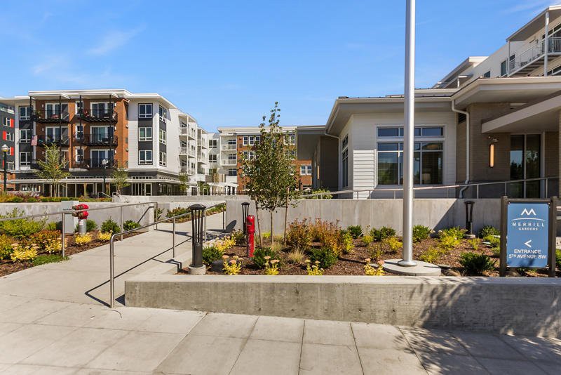 A modern apartment complex with landscaped gardens and concrete pathways.