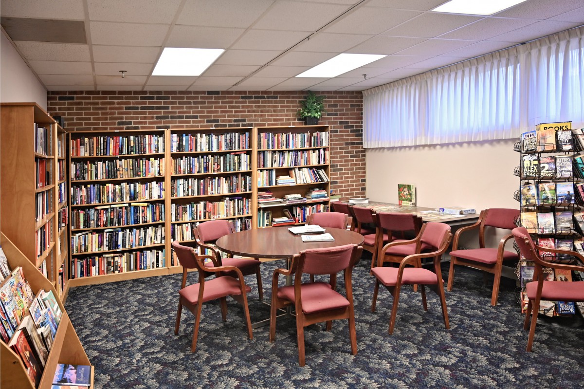 A cozy library corner with bookshelves, a round table, and chairs.