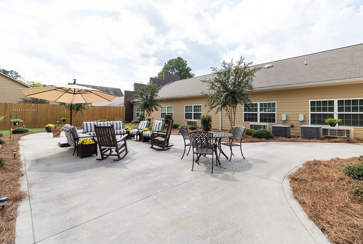 A spacious patio with seating and umbrellas in a backyard setting.