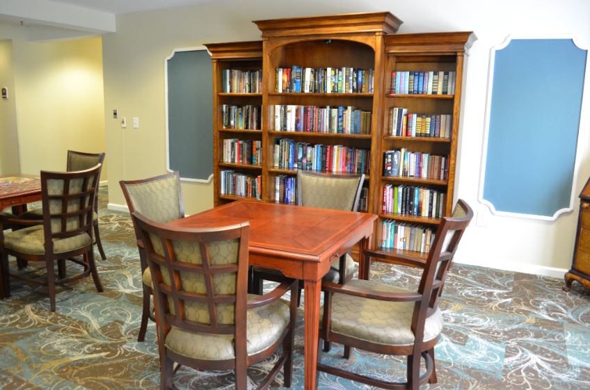 A cozy library corner featuring a wooden table, chairs, and a fully stocked bookshelf.