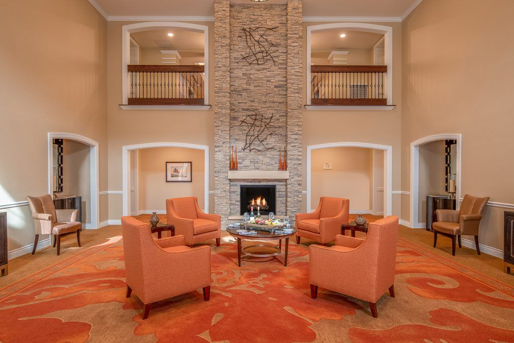A cozy living room featuring a stone fireplace and a seating area with orange armchairs.