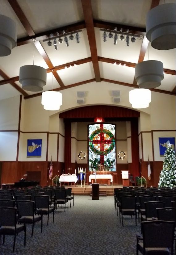 Interior of a church decorated for Christmas with a view of the altar and stained glass window.