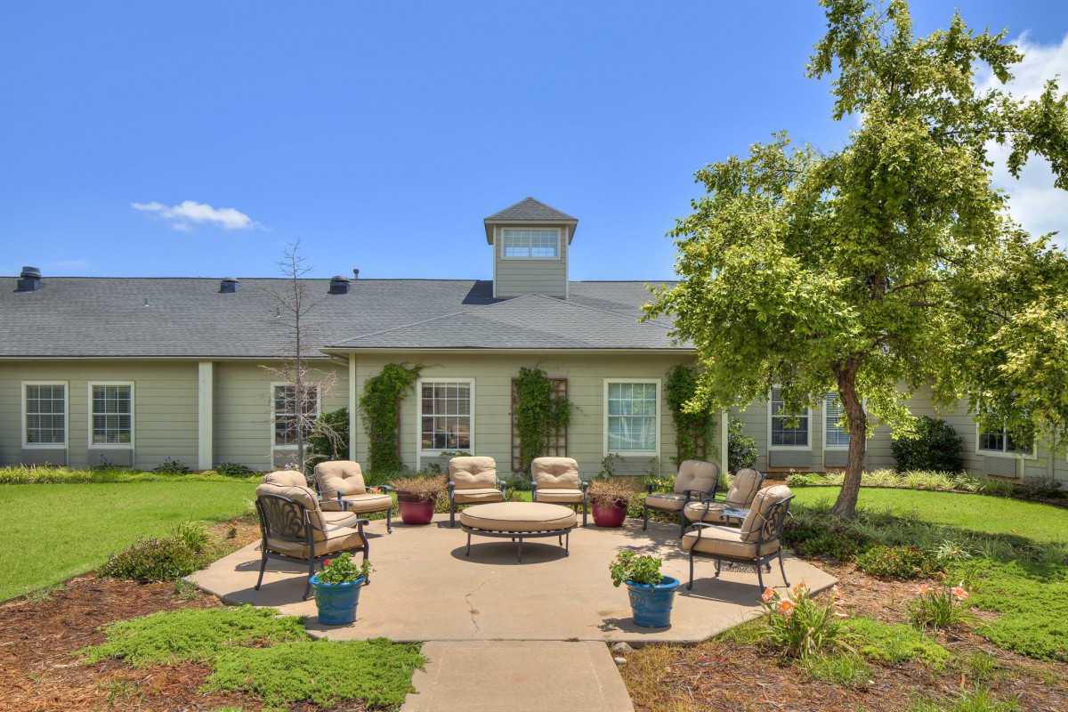 A cozy outdoor patio area with comfortable seating surrounded by greenery.