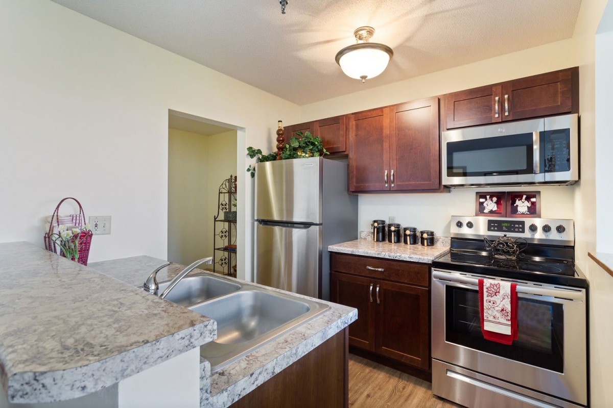 A modern kitchen with stainless steel appliances and wood cabinetry.