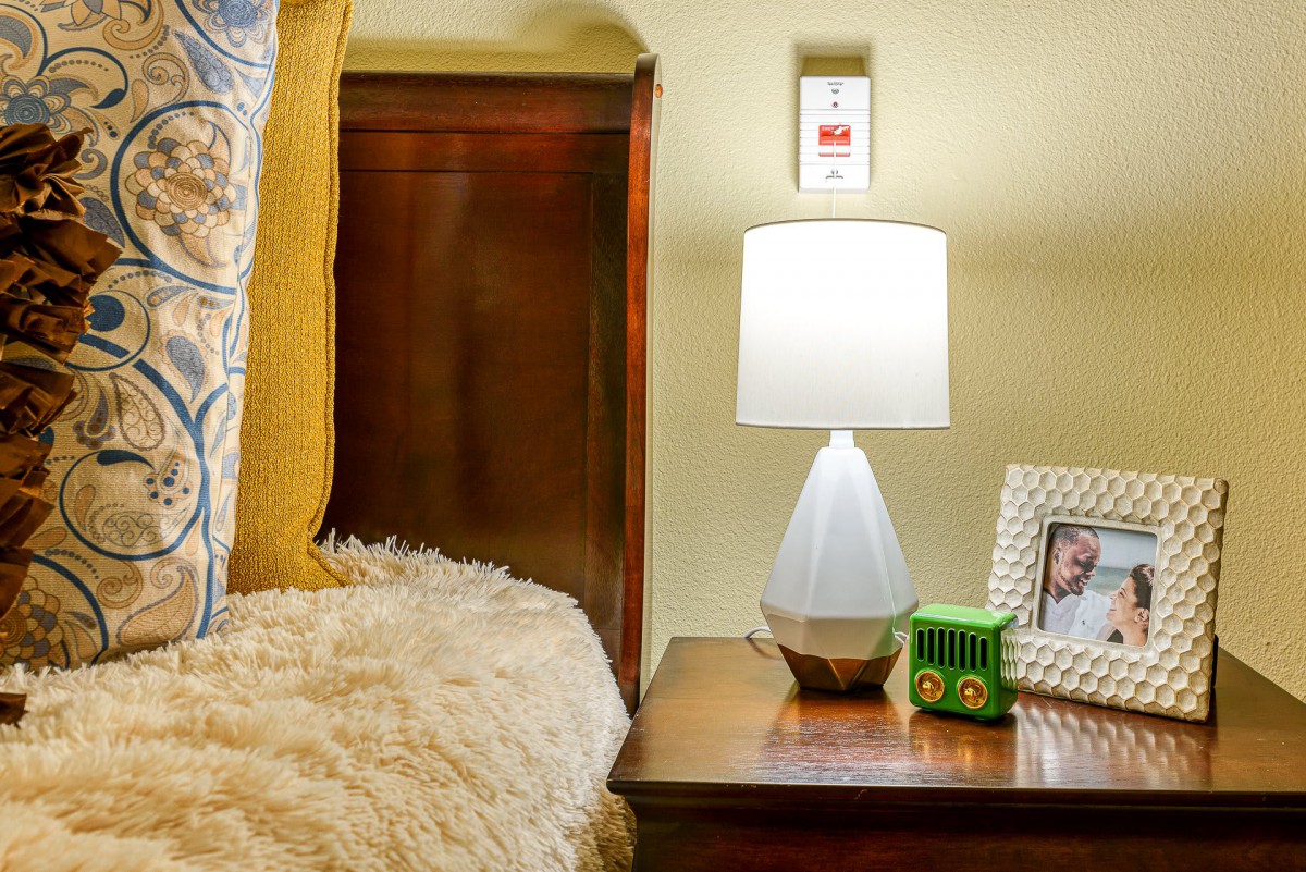 A cozy bedroom nightstand with a lamp, photo frame, and decor items.