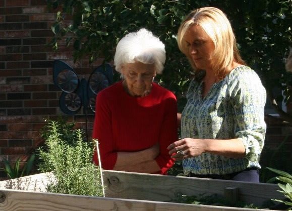 Two women are engaged in gardening together, enjoying the outdoors.