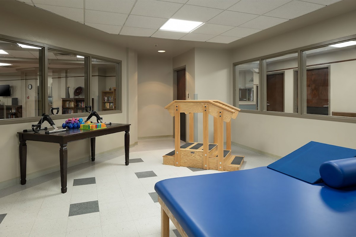 A rehabilitation room equipped with a therapy table and wooden stairs for physical exercises.