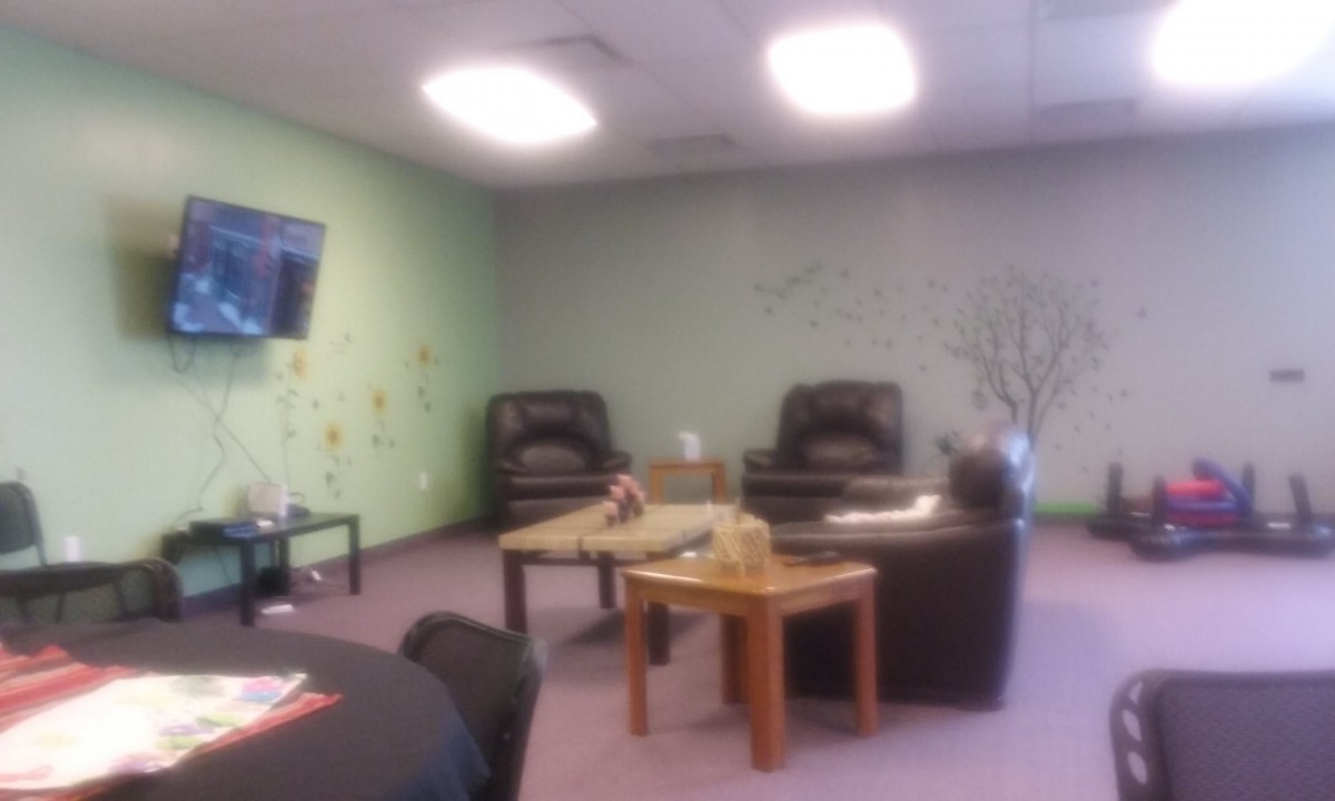 A cozy lounge area with chairs, a coffee table, and a television on the wall.