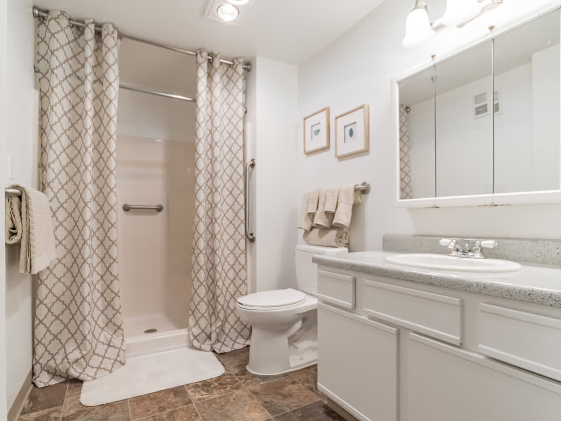 A clean and modern bathroom with a shower, toilet, and sink.