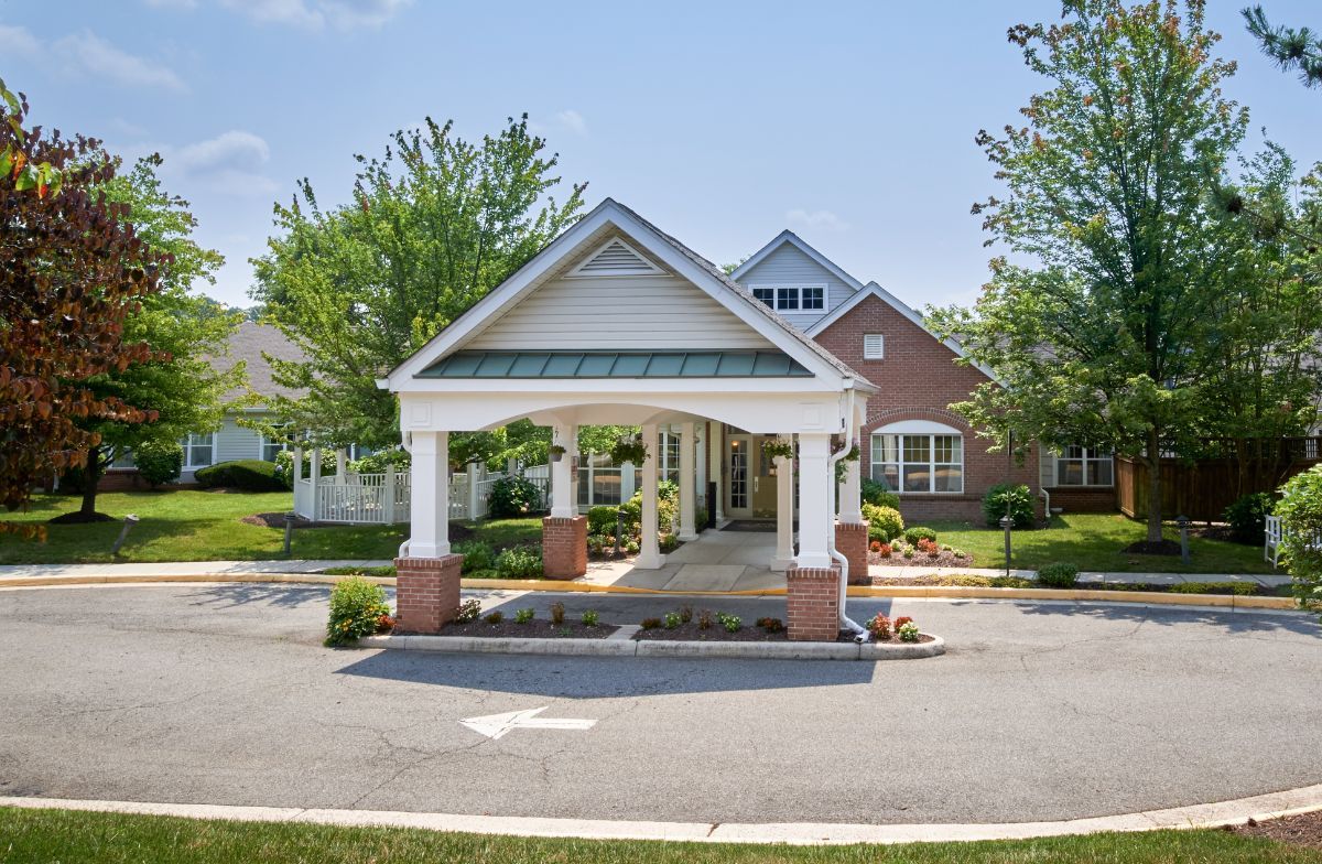 A residential building entrance with a covered driveway and surrounding greenery.