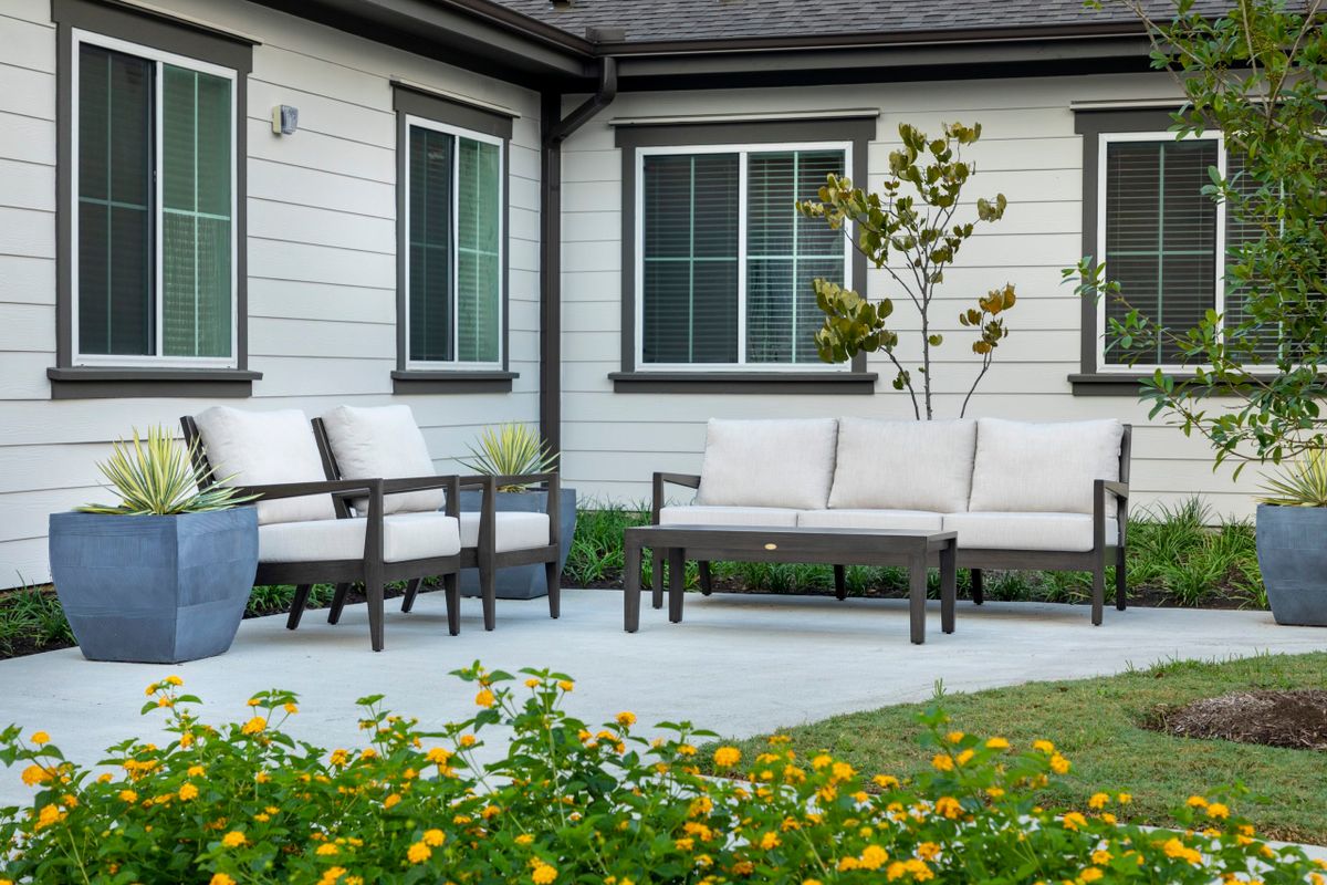 A modern patio with comfortable outdoor seating surrounded by a well-maintained garden.