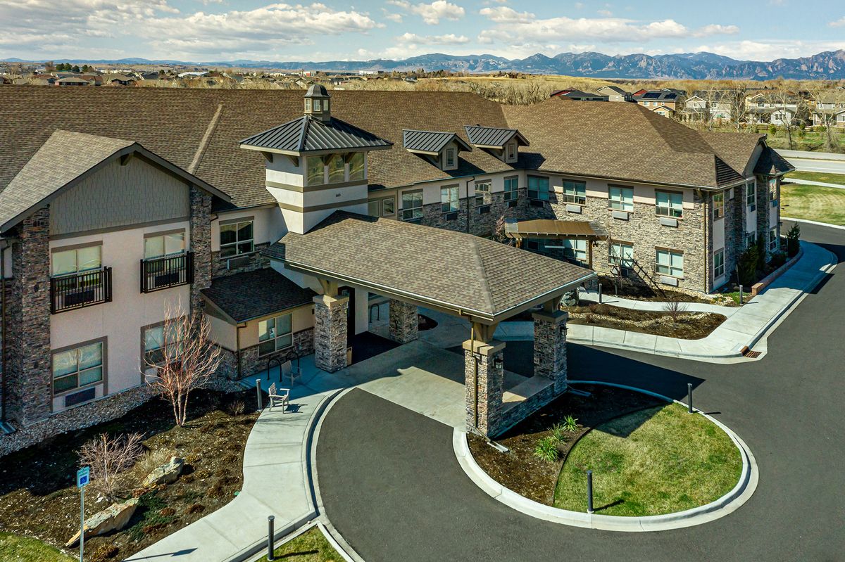 Aerial view of a large building with an entrance driveway and scenic mountain backdrop.