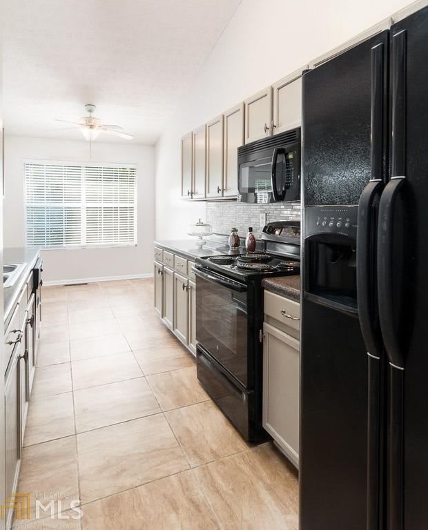 A modern kitchen with black appliances and tile flooring.