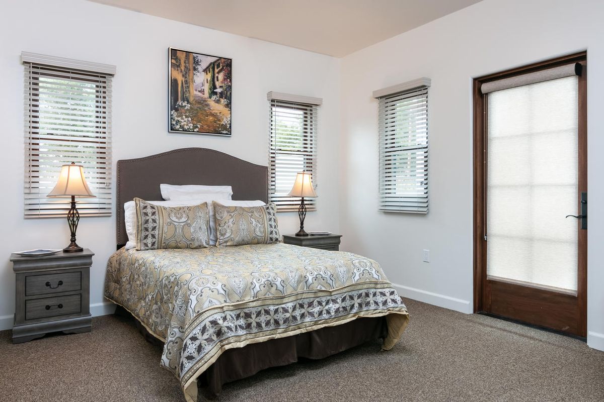 A cozy bedroom with a bed, decorative pillows, and a lamp by the window.