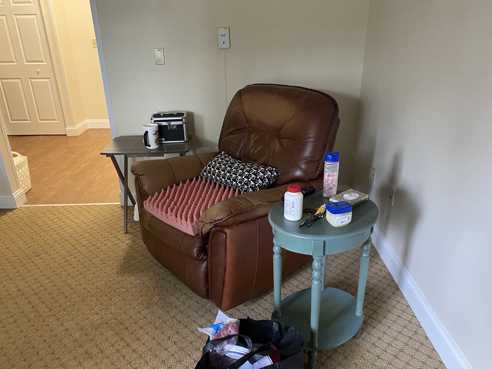 A cozy living room corner with a recliner, side table, and various items for comfort.
