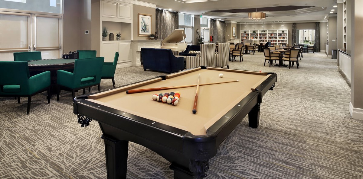 A cozy living room featuring a billiards table with cue sticks ready for a game.