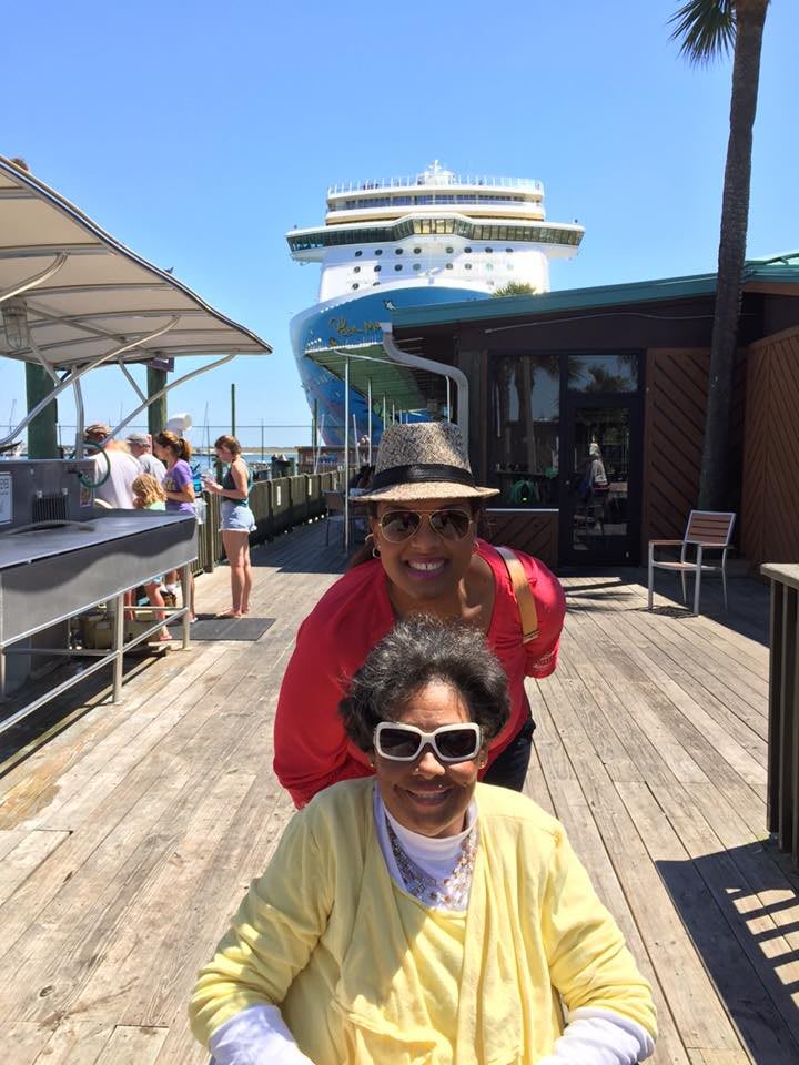 Two people enjoying a sunny day on the dock near a cruise ship.