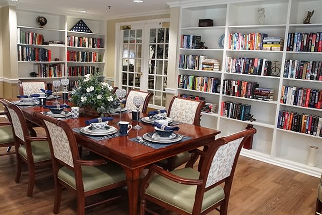 A cozy dining room featuring a set table and bookshelves filled with books.