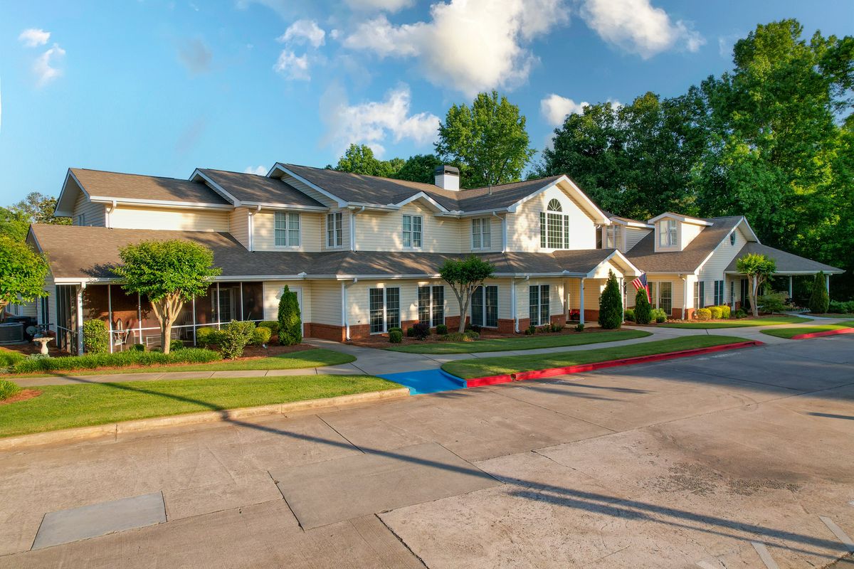A picturesque suburban residential building with well-maintained landscaping and a clear sky.