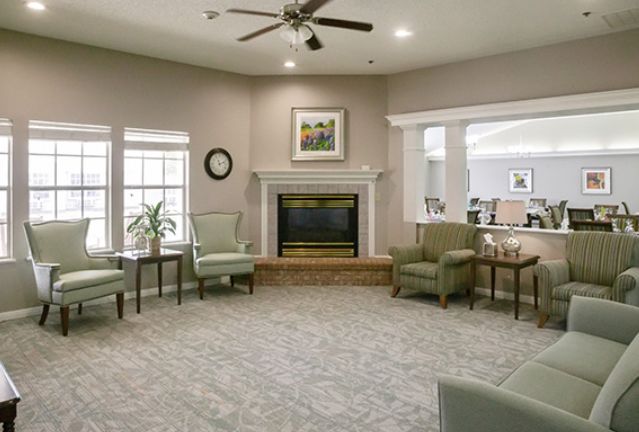 A cozy living room with a fireplace, armchairs, and soft lighting.