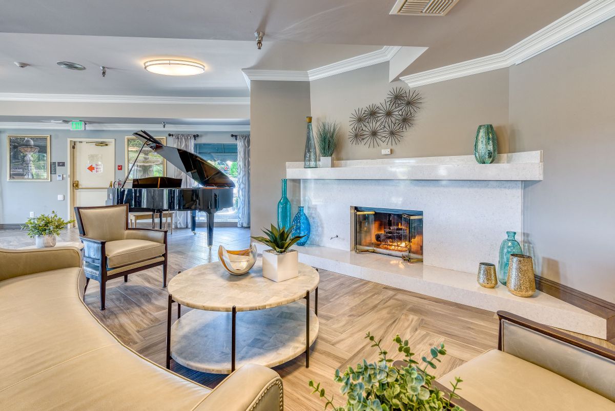 A modern living room featuring elegant furniture, a cozy fireplace, and a grand piano.