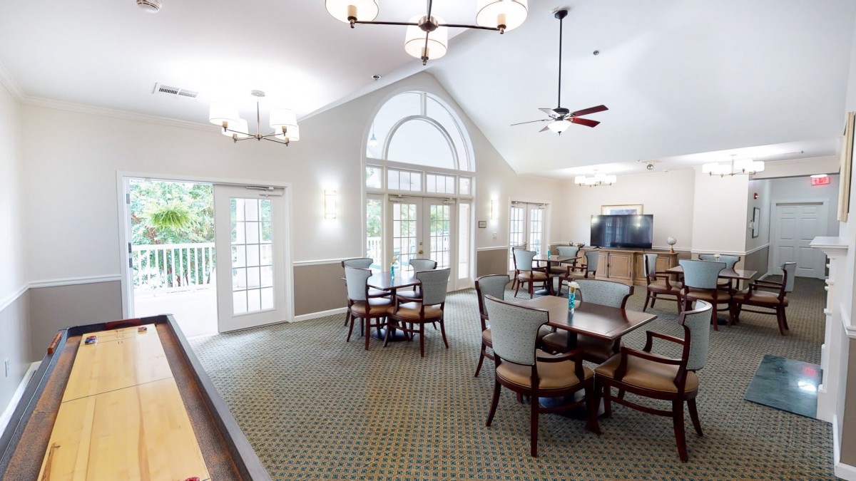 A cozy dining area with multiple tables and chairs, featuring large windows and elegant lighting.