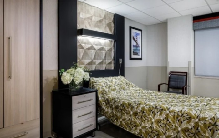 A modern hospital room with a neatly made bed and stylish decor.
