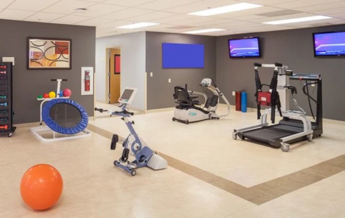 A modern gym with various exercise equipment including a treadmill and stationary bikes.