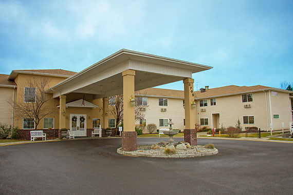 Exterior view of a hotel entrance with a covered driveway and parking area.
