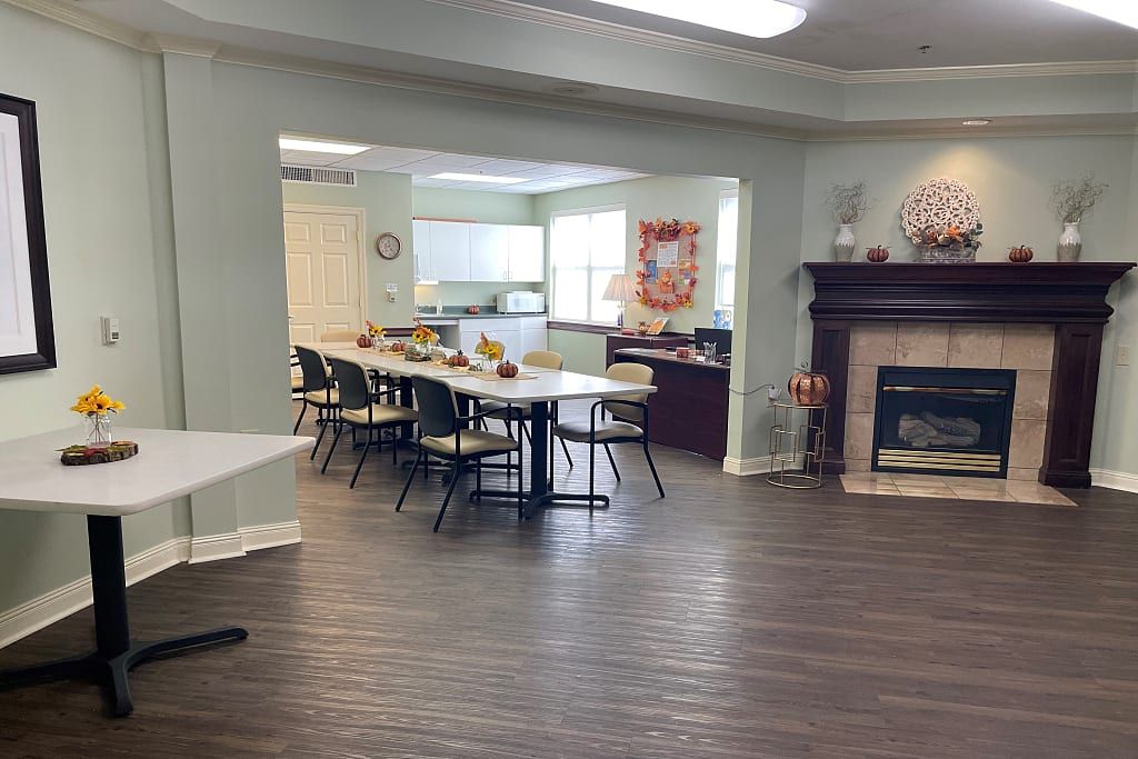 A cozy dining area with tables and chairs set up near a kitchen and fireplace.