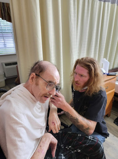 A caregiver attentively assists an elderly individual indoors.