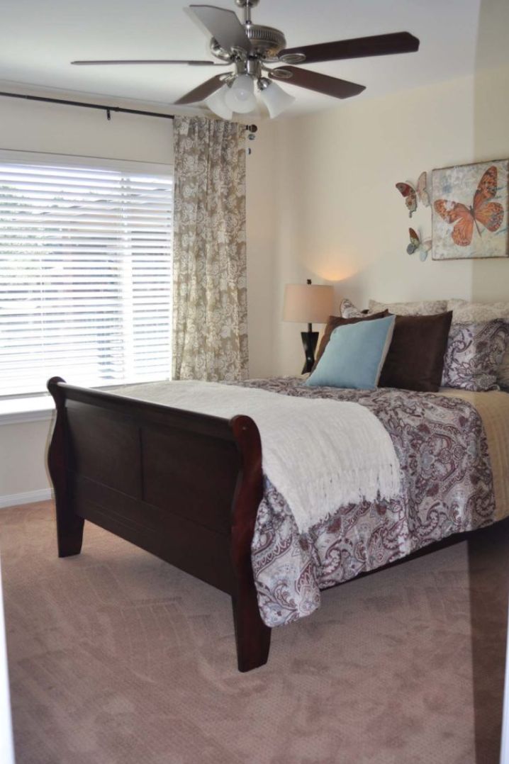 A cozy bedroom with a neatly made bed, decorative pillows, and a butterfly artwork on the wall.