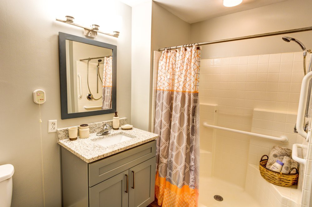 A modern bathroom with a vanity, mirror, and shower area featuring a patterned curtain.