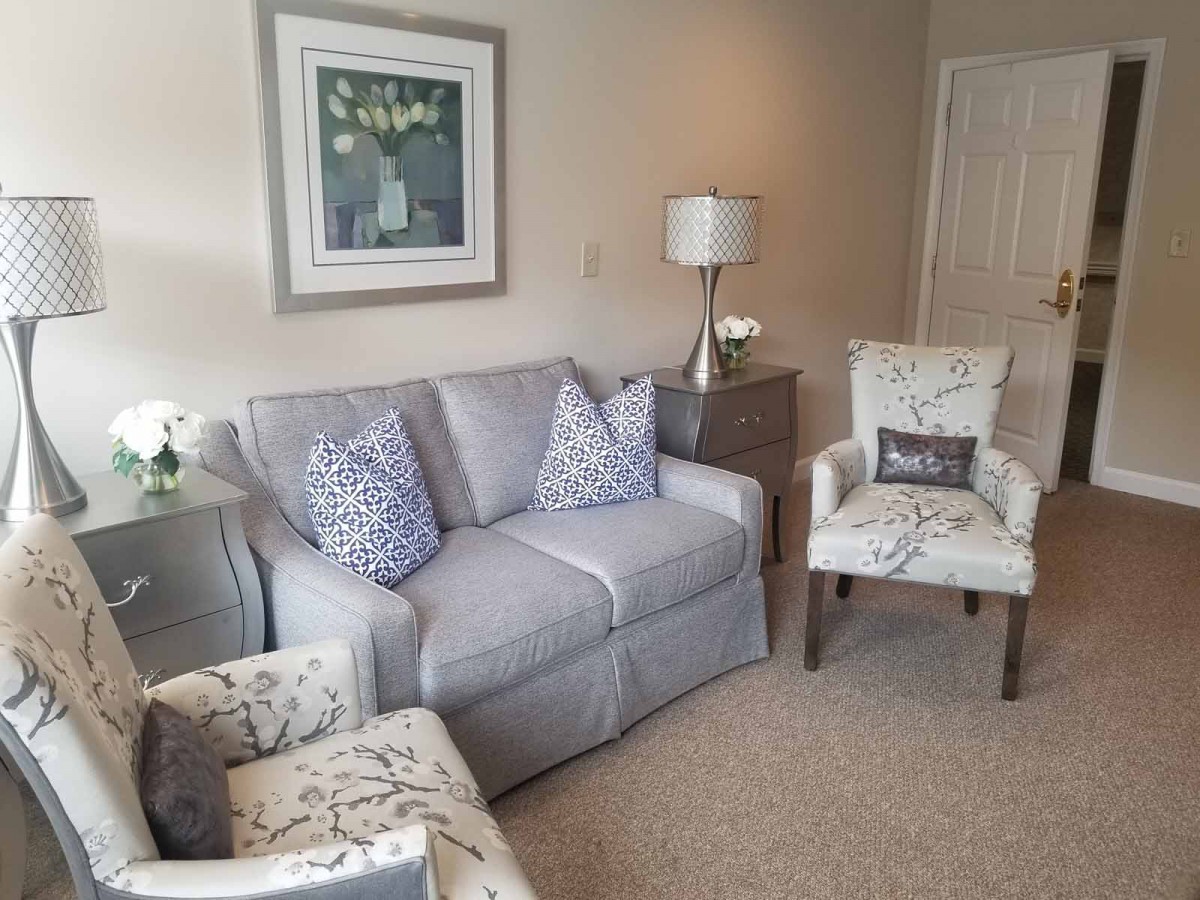 A cozy living room with a gray sofa, patterned armchairs, and stylish decor.