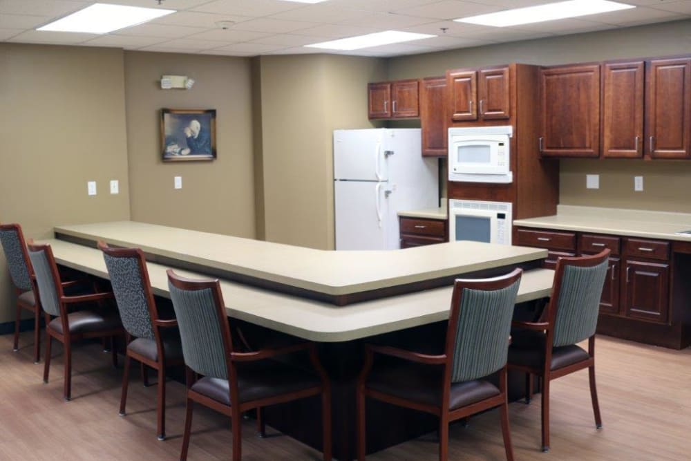 A modern kitchen and conference area with seating and appliances.