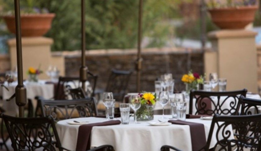 An elegantly set outdoor restaurant table with flowers and glassware.