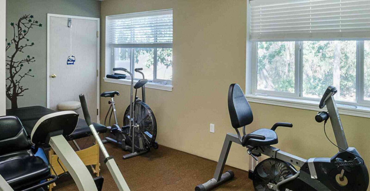 A small gym with exercise bikes and fitness equipment by the windows.