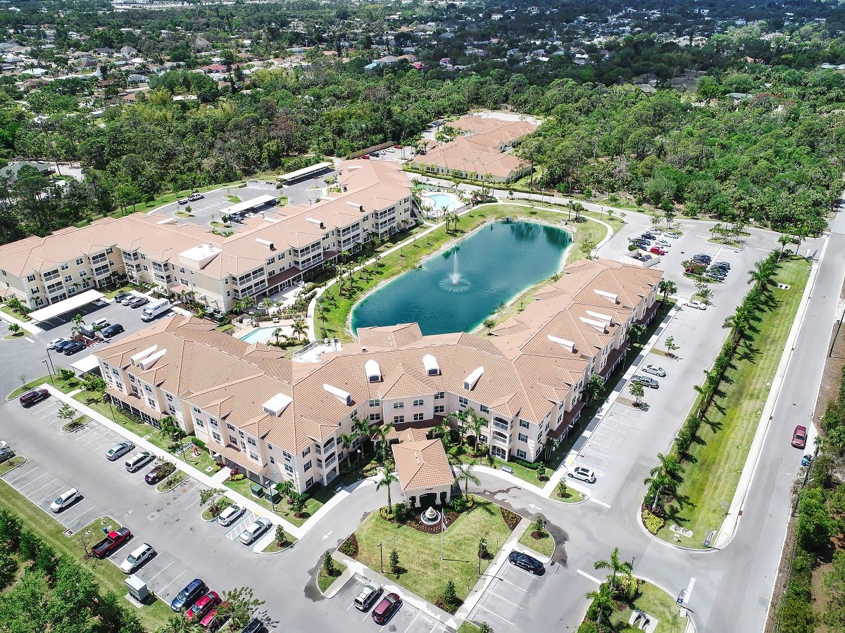 Aerial view of a building complex with a central lake and surrounding greenery.