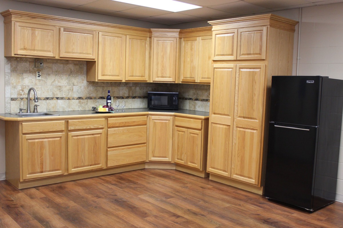 A modern kitchen with wooden cabinets and a black refrigerator.
