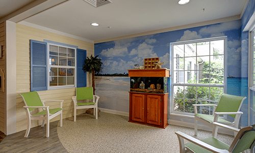 A cozy indoor seating area with an aquarium and scenic mural.