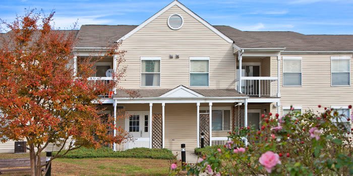 A two-story suburban duplex with a covered porch and a landscaped front yard.