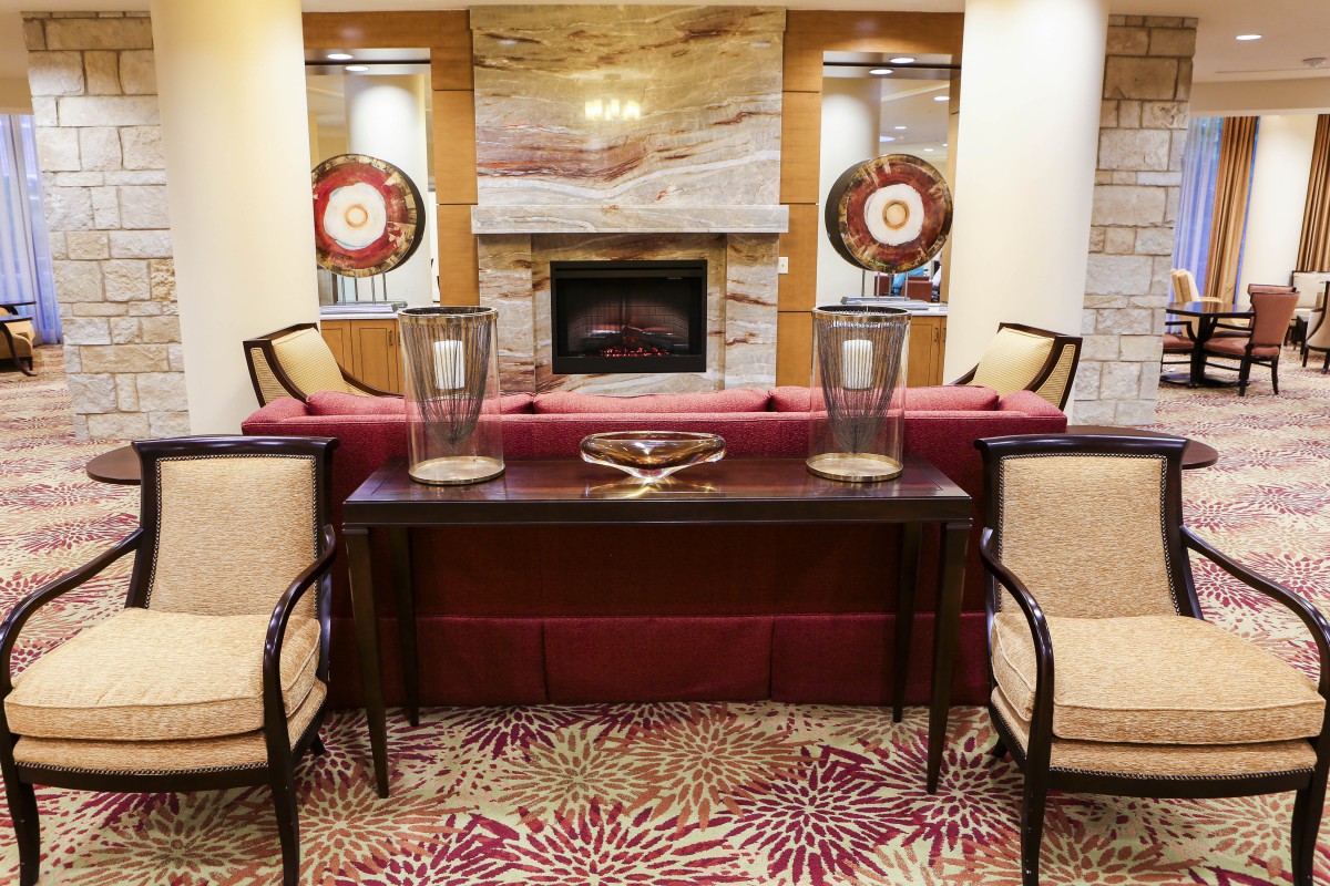 A cozy living room with a central fireplace, surrounded by comfortable chairs and elegant decor.