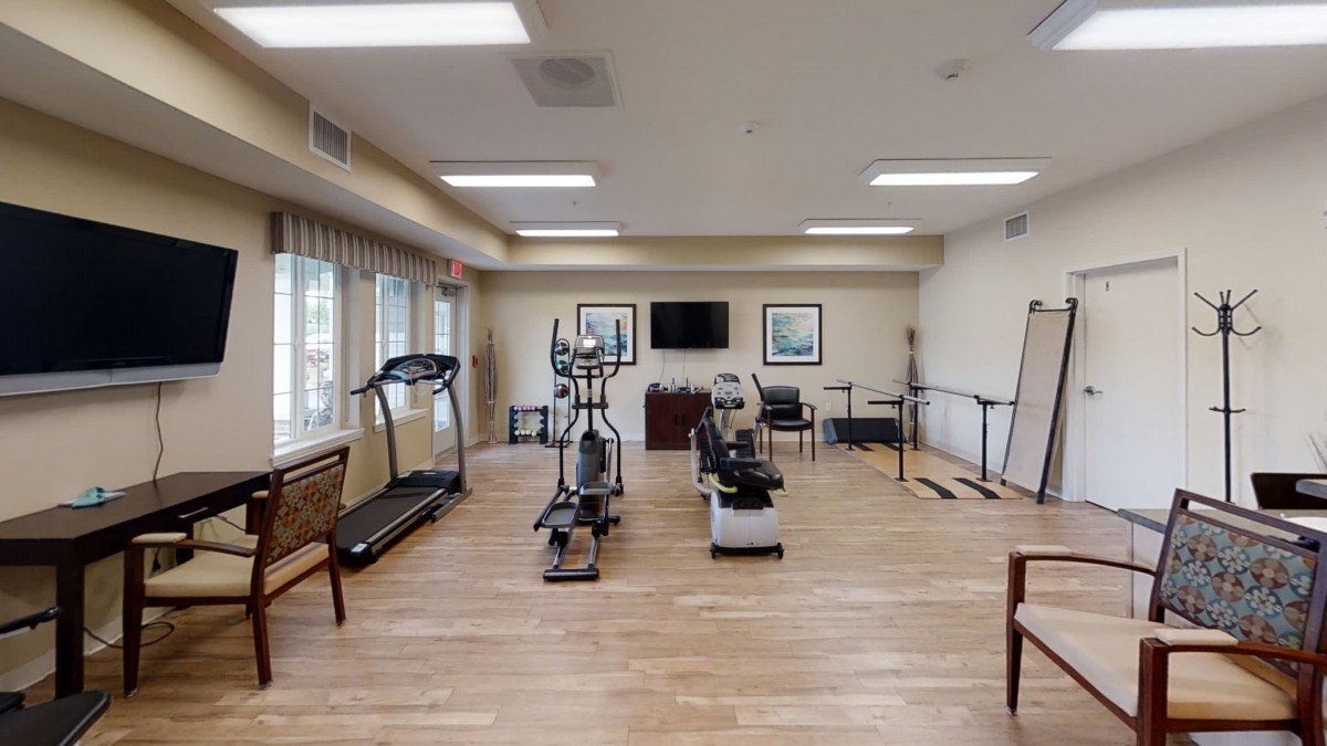 A well-equipped exercise room with various gym machines and a wooden floor.
