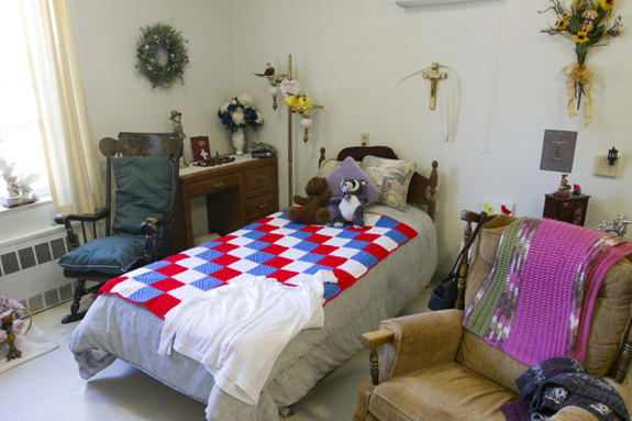 A cozy bedroom with a colorful quilt on the bed and decorative items around.