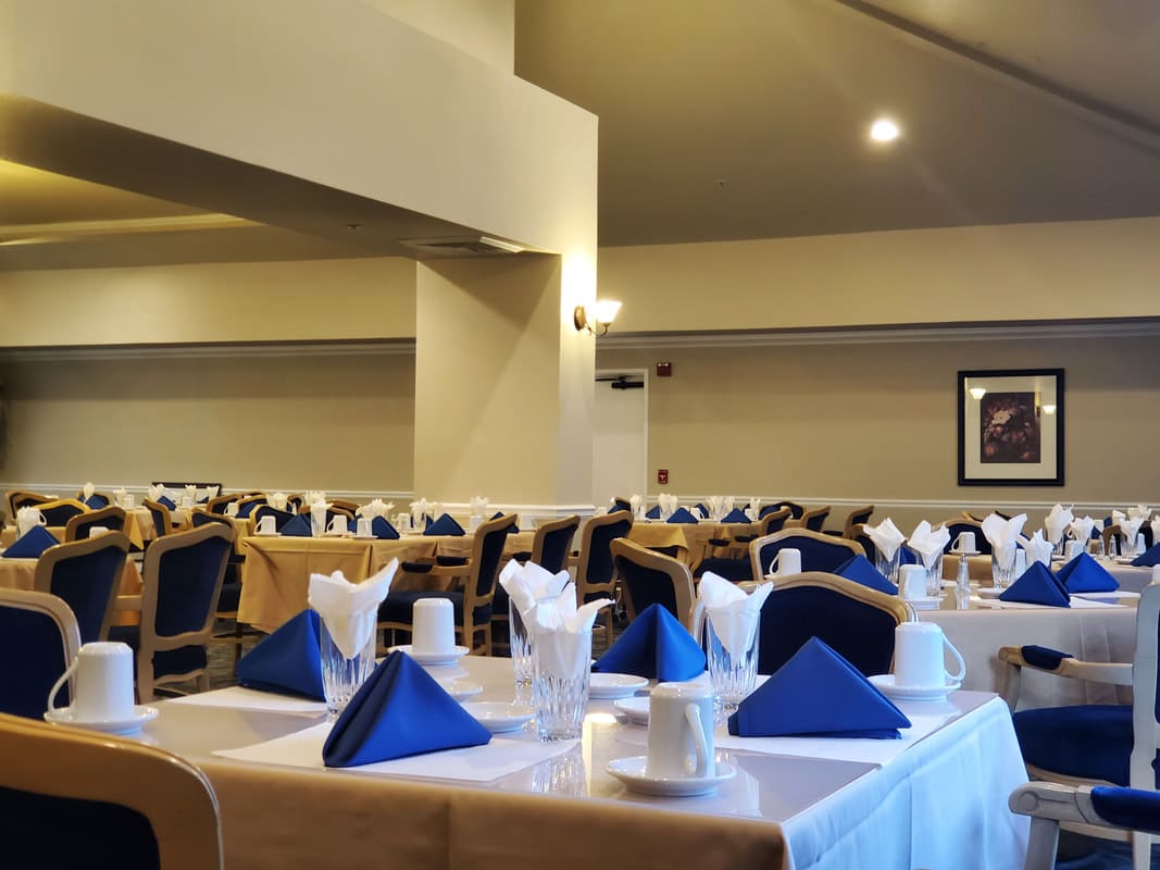 A well-arranged restaurant dining area with neatly set tables featuring blue napkins and white tablecloths.